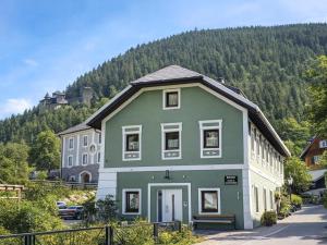 een groen en wit gebouw met een berg op de achtergrond bij Schloßblick in Ramingstein