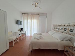 een witte slaapkamer met een bed en een bureau bij Casa del Sole Guest House in Alghero