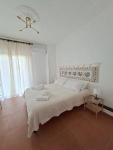 een witte slaapkamer met een groot bed en een lamp bij Casa del Sole Guest House in Alghero +7 foto's