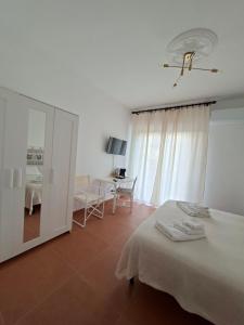 een witte slaapkamer met een bed en een bureau bij Casa del Sole Guest House in Alghero