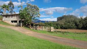 an old barn on a field next to a dirt road at Casa Manarin in Água Boa