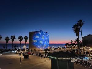 a large blue building on a beach with palm trees at Casa del Sole Guest Rooms in Alghero +12 photos
