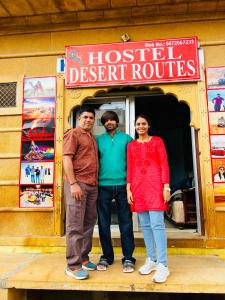 tre persone in piedi davanti al ristorante di un ostello di Hostel Desert Routes a Jaisalmer