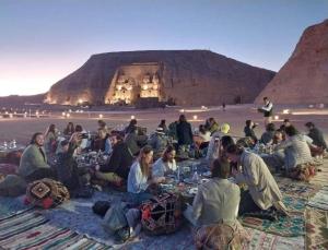 a group of people sitting on the beach eating food at Hllol Hotel Abu Simbel in Abu Simbel