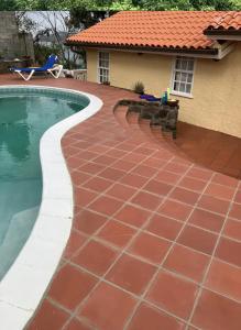 a swimming pool with a red tile floor next to a house at Uniek Villa in Gros Islet