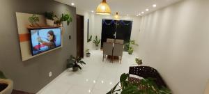 a living room with potted plants and a tv on a wall at Doce lar in Búzios