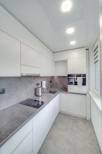 a white kitchen with white cabinets and a window at AR Rezidencia Rosná in Košice
