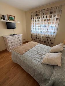 a bedroom with a bed and a dresser with a television at Apartamento vital centrico in Lanjarón +6 photos