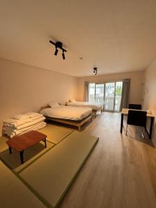 a room with two beds and rugs in it at 浦添民泊ejuイージュ in Urazoe