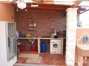 a kitchen with a washing machine and a brick wall at Casa Vacanze Fontane Bianche in Fontane Bianche