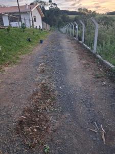 a dirt road with a fence next to a house at Recanto do Daniel in Irati