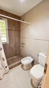 a white bathroom with a toilet and a shower at Casa Bouchard in Valeria del Mar