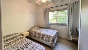 two beds in a small room with a window at Casa Bouchard in Valeria del Mar