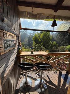 a table and two stools on a porch with a view at Cabaña en la Calera BersaNina in La Calera +12 photos