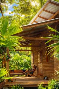 een stel zit op de veranda van een huis bij Madre Selva Eco Lodge in Nuquí