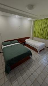 two beds in a room with green curtains at Apartamento com 4 suítes em Salinas - Pa in Salinópolis