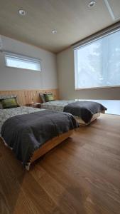 two beds in a bedroom with a large window at Hakuba Powder Cottage Eden in Hakuba