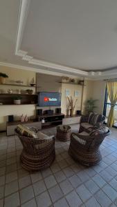 a living room with wicker chairs and a flat screen tv at Apartamento com 4 suítes em Salinas - Pa in Salinópolis
