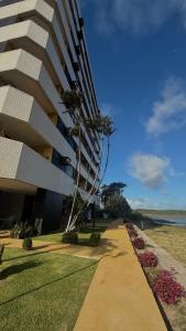 a tall building with a palm tree next to a sidewalk at Apartamento com 4 suítes em Salinas - Pa in Salinópolis