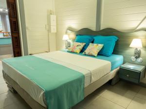 a bedroom with a large bed with blue pillows at Bungalow Brise Marine - Plaisir d Évasion in Deshaies