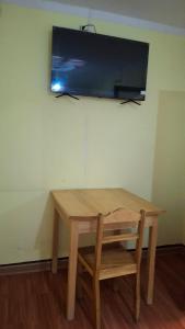 un tavolo in legno con sedia e una televisione su una parete di Alojamiento la Gran Estación a Uyuni