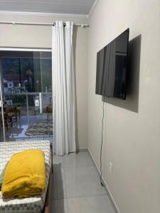 a living room with a tv on a wall at Casa aconchegante à 2 minutos da praia em Prainha de Mambucaba Paraty in Paraty