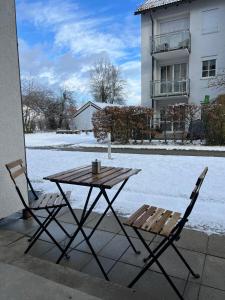 a table and two chairs with snow on the ground at Apartment Sebald in Ingolstadt +4 photos
