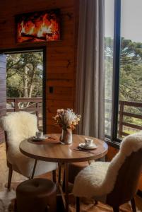 a table with two chairs and a vase of flowers at Flor da serra in Urubici