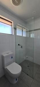 a bathroom with a toilet and a glass shower at Albatross Motel in Lakes Entrance +3 photos