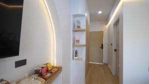 a hallway with a white wall with shelves and a television at บ้านระเบียงทะเล หัวหิน in Hua Hin