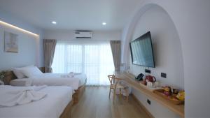 a hotel room with two beds and a desk at บ้านระเบียงทะเล หัวหิน in Hua Hin