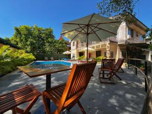 a table and chairs with an umbrella next to a pool at Monkey Republic Kampot in Kampot