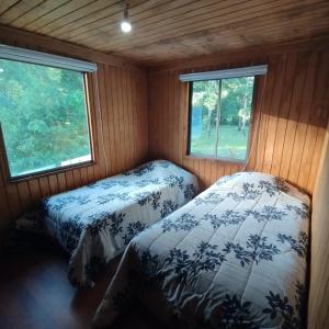 two beds in a small room with two windows at HOSTAL CARHUELLO in Pucón