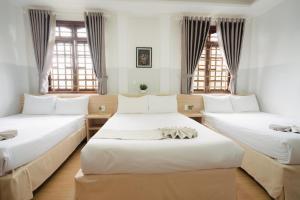 two beds in a room with two windows at Ngoc Nguyen Anh Hotel Da Lat in Da Lat