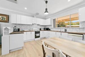 a kitchen with white cabinets and a wooden table at Holiday house in Roleystone +27 photos