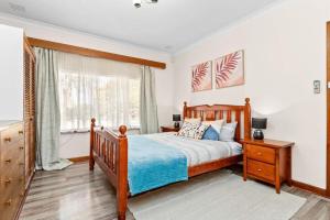a bedroom with a wooden bed and a window at Holiday house in Roleystone