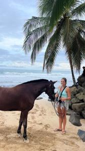 a woman standing next to a horse on the beach at Casa Pelicano in Bocas Town