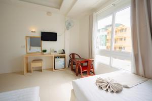 a white room with a bed and a desk and a window at Ngoc Nguyen Anh Hotel Da Lat in Da Lat