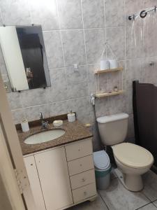 een badkamer met een toilet, een wastafel en een spiegel bij Suíte brisa do litoral in Arraial do Cabo