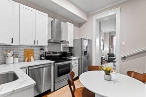 a kitchen with white cabinets and a white table and chairs at The Bricklight | Elevated 3BR + Parking in Soulard in Saint Louis +30 photos