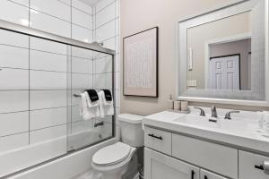 a bathroom with a toilet and a sink and a mirror at The Bricklight | Elevated 3BR + Parking in Soulard in Saint Louis