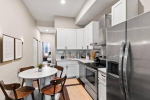 a kitchen with a table and a stainless steel refrigerator at The Bricklight | Elevated 3BR + Parking in Soulard in Saint Louis
