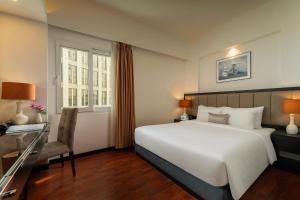 a hotel room with a large bed and a chair at Ja Cosmo Hotel and Spa in Hanoi