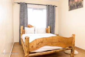 a bedroom with a wooden bed in front of a window at Mupa Luxury Condo IV BnB in Nyahururu