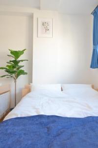 a bedroom with a white bed and a plant at ゲストハウス夢宿 in Osaka