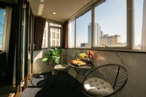 河内Ja Cosmo Hotel and Spa的阳台配有两把椅子和一张带水果的桌子。