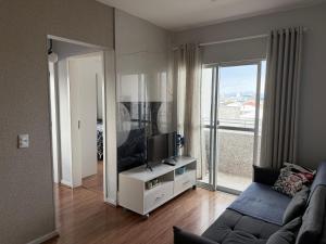 een woonkamer met een bank en een flatscreen-tv bij Lindo apartamento completo e com garagem coberta in Palhoça