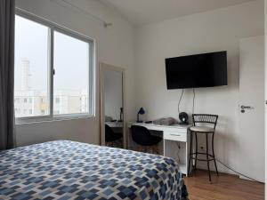 een slaapkamer met een bed en een bureau met een computer bij Lindo apartamento completo e com garagem coberta in Palhoça +7 foto's