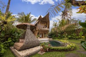 a villa with a hammock in front of a house at Lazy Coconut Bali in Gianyar