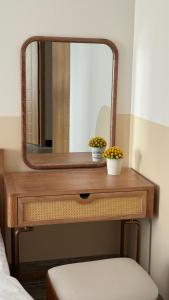 a wooden dressing table with a mirror and flowers on it at Moon Hotel Buôn Hồ in Buôn Tring